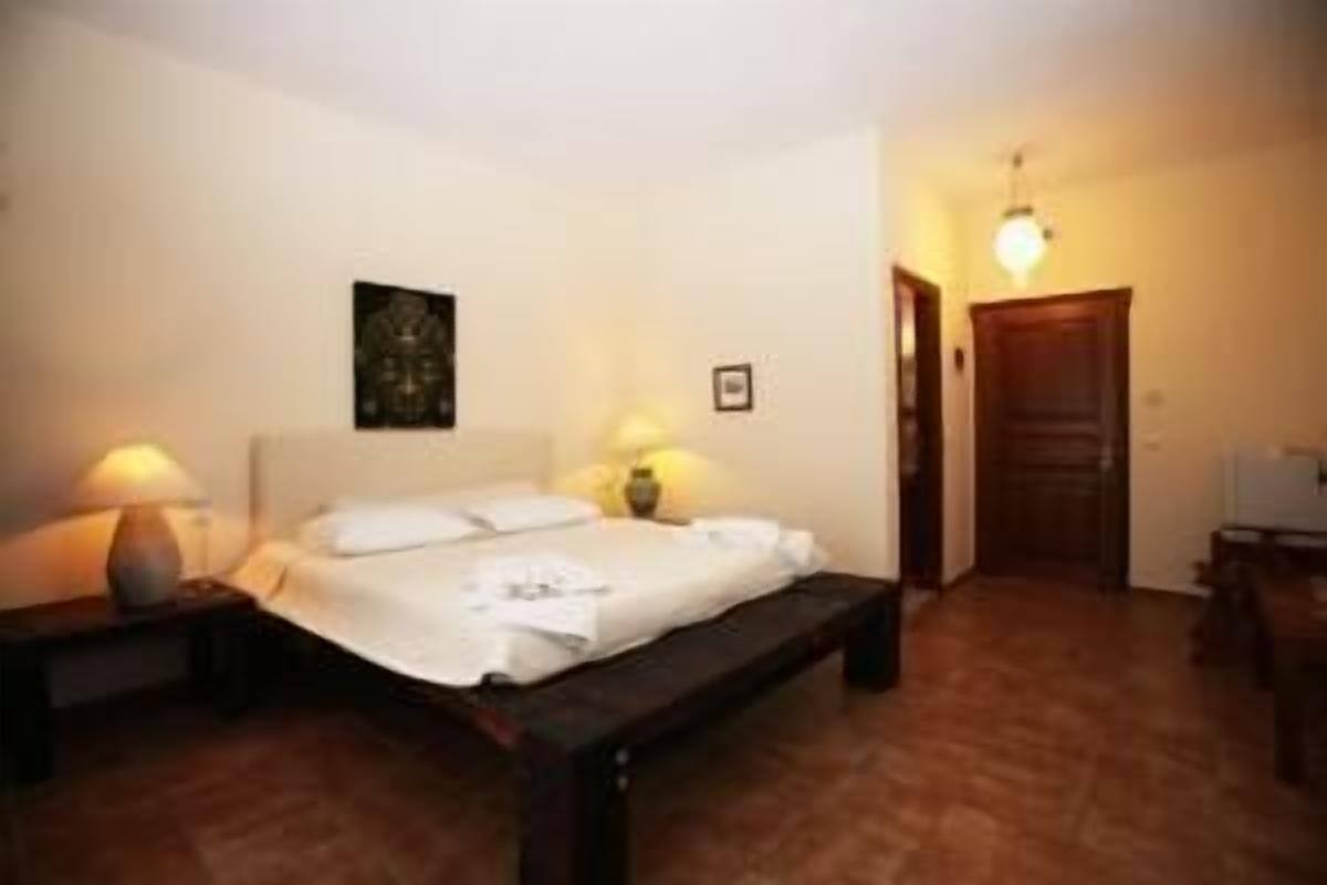 A bedroom with a bed, bedside lamps, a wooden bench, and a door.