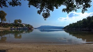 Ein ruhiger Fluss mit Booten, ein Sandstrand und ein Berg in der Ferne.