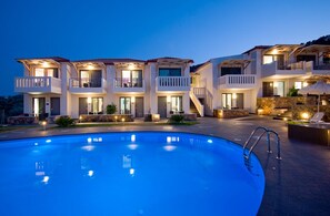 Una piscina al aire libre, sombrillas, sillones reclinables de piscina