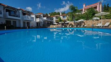 Relax by the pool surrounded by lounge chairs and umbrellas, with stunning views of the surrounding architecture.