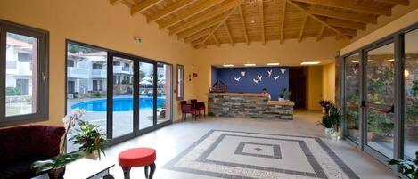 Un vestíbulo amplio con techo de madera, una recepción y vistas a la piscina.