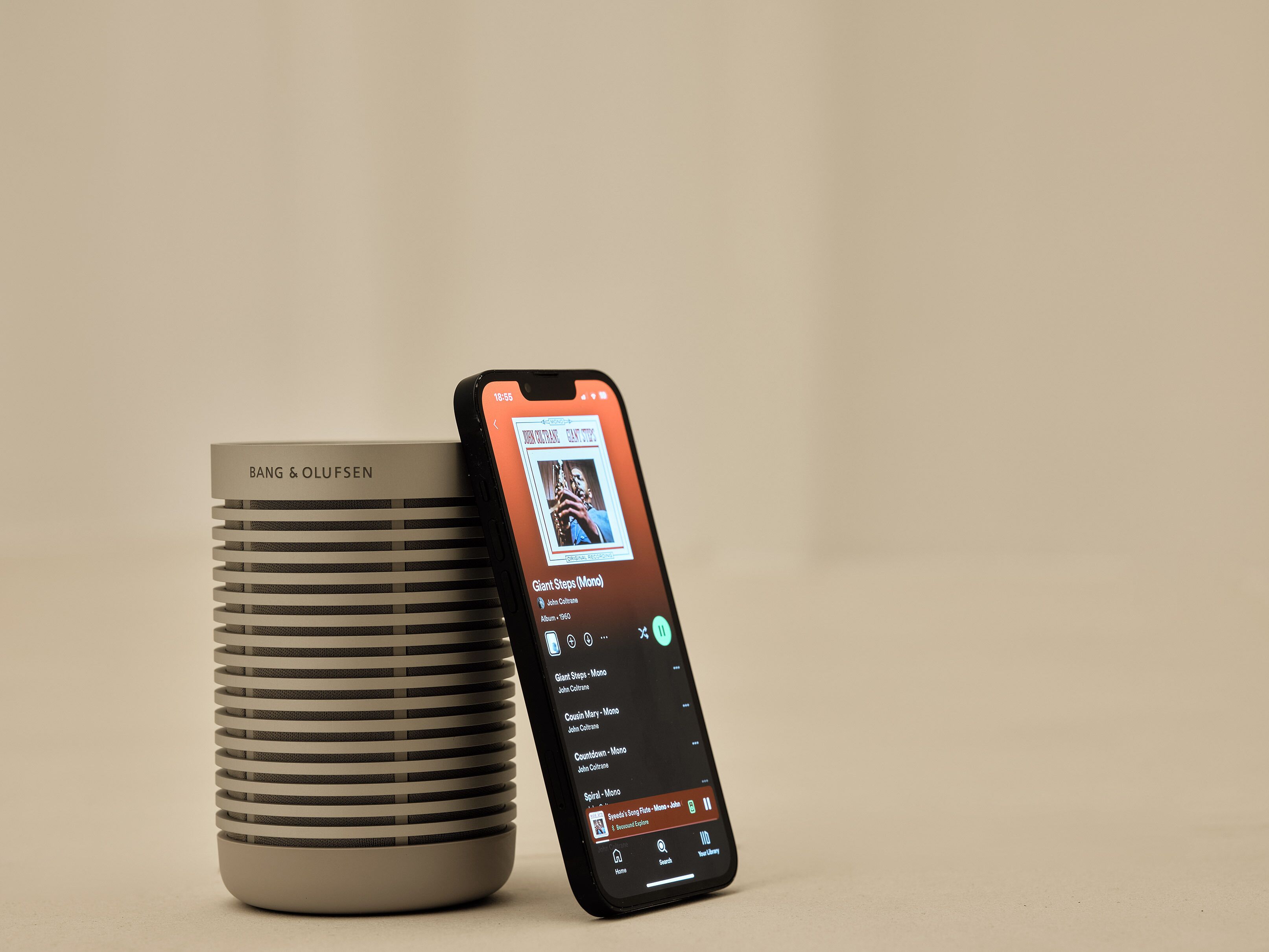 A smartphone displaying a music app interface with a vinyl record player in the background.