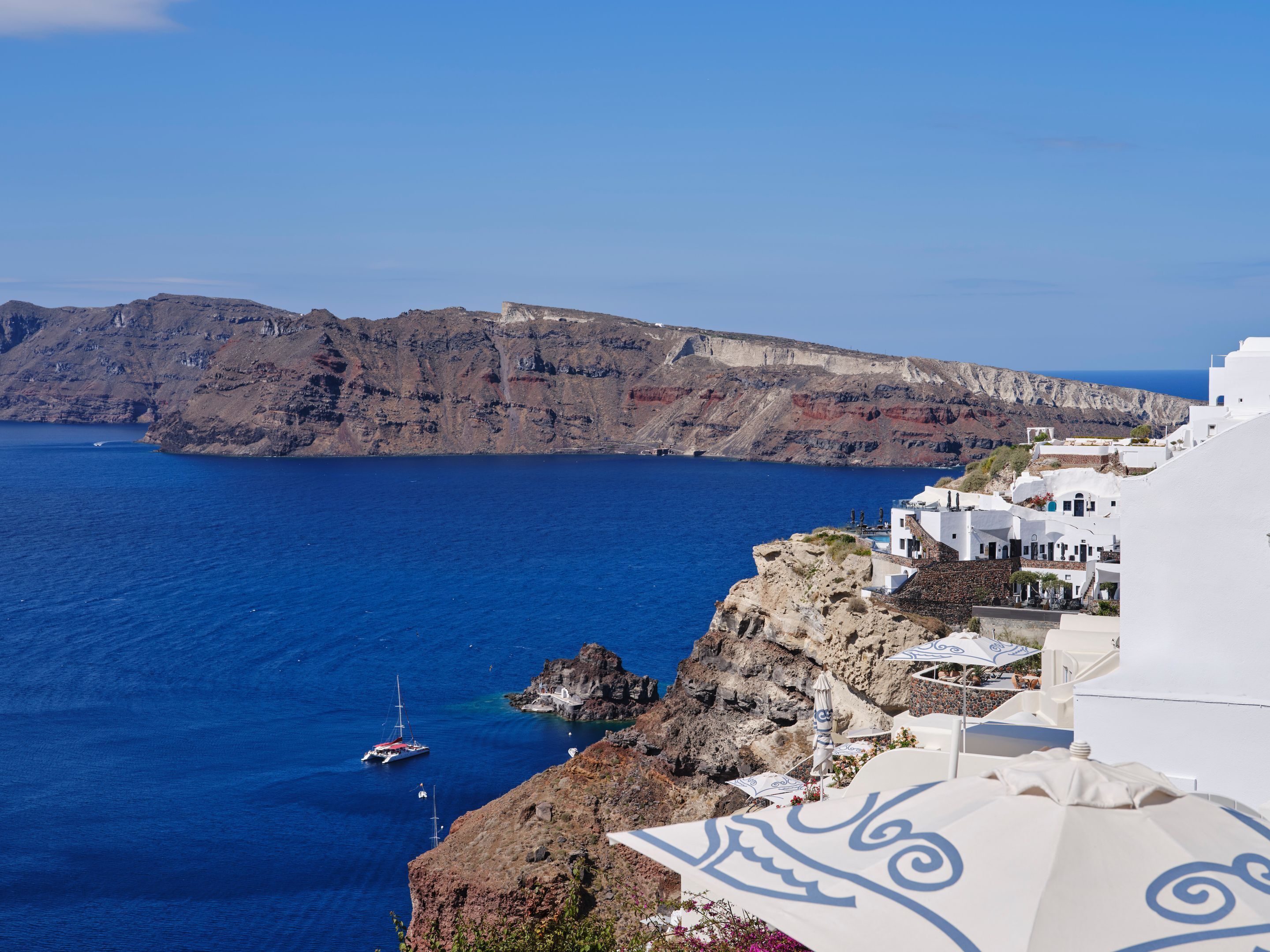 Vista costera con edificios blancos, un acantilado rocoso y un mar azul cristalino.