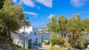 A coastal street with a white building, a lamp post, and a car parked in front. - Villa Ariadni (Skiathos)