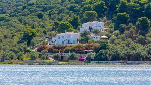A coastal property with multiple white buildings, surrounded by lush greenery and a body of water. - Villa Ariadni (Skiathos)