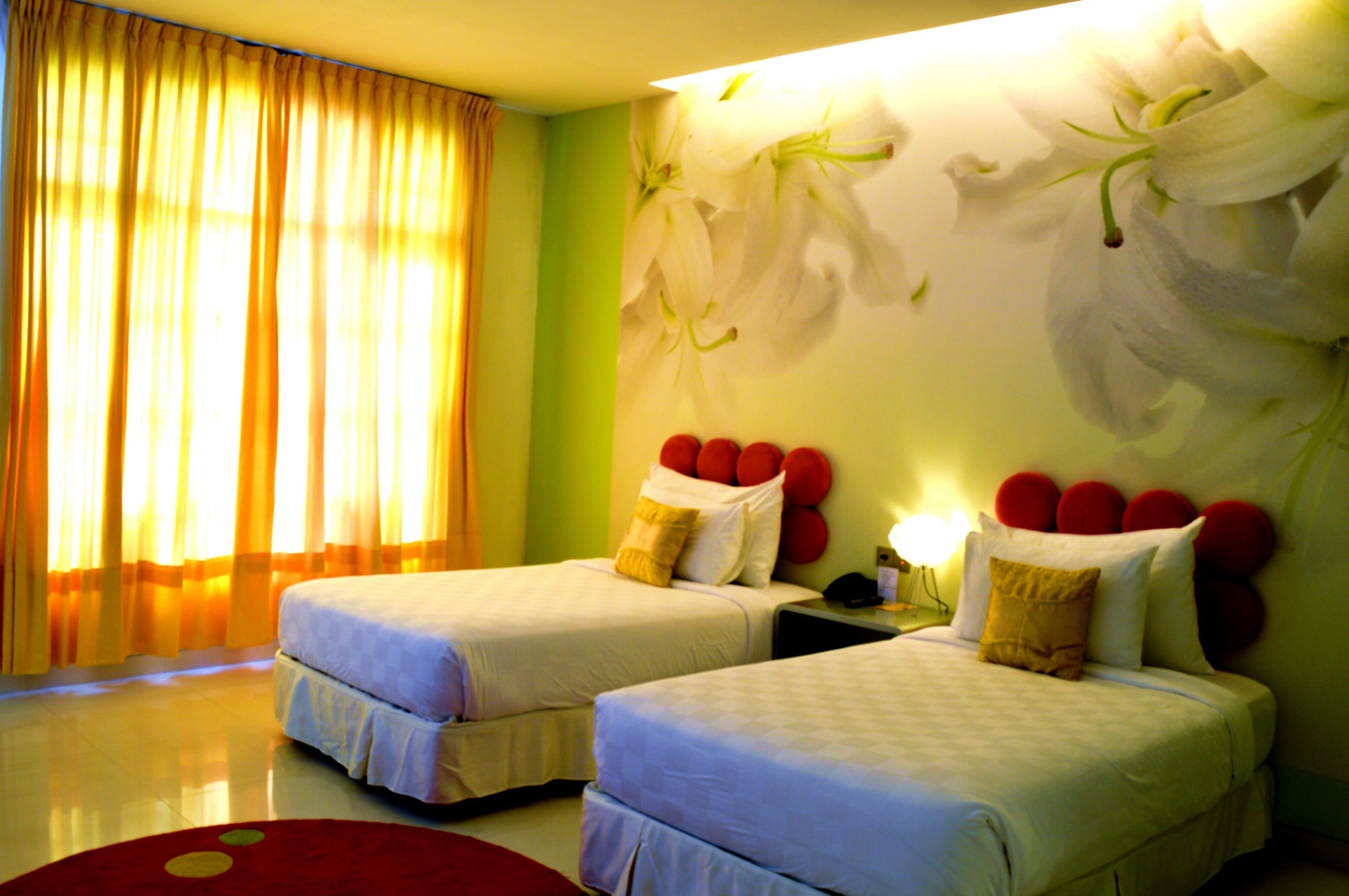 Een hotelkamer met twee bedden, een rond rood tapijt en een bloemendecor op de muur.