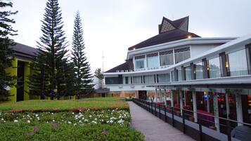 A modern building with a glass facade, a landscaped garden with flowers, and tall trees.
