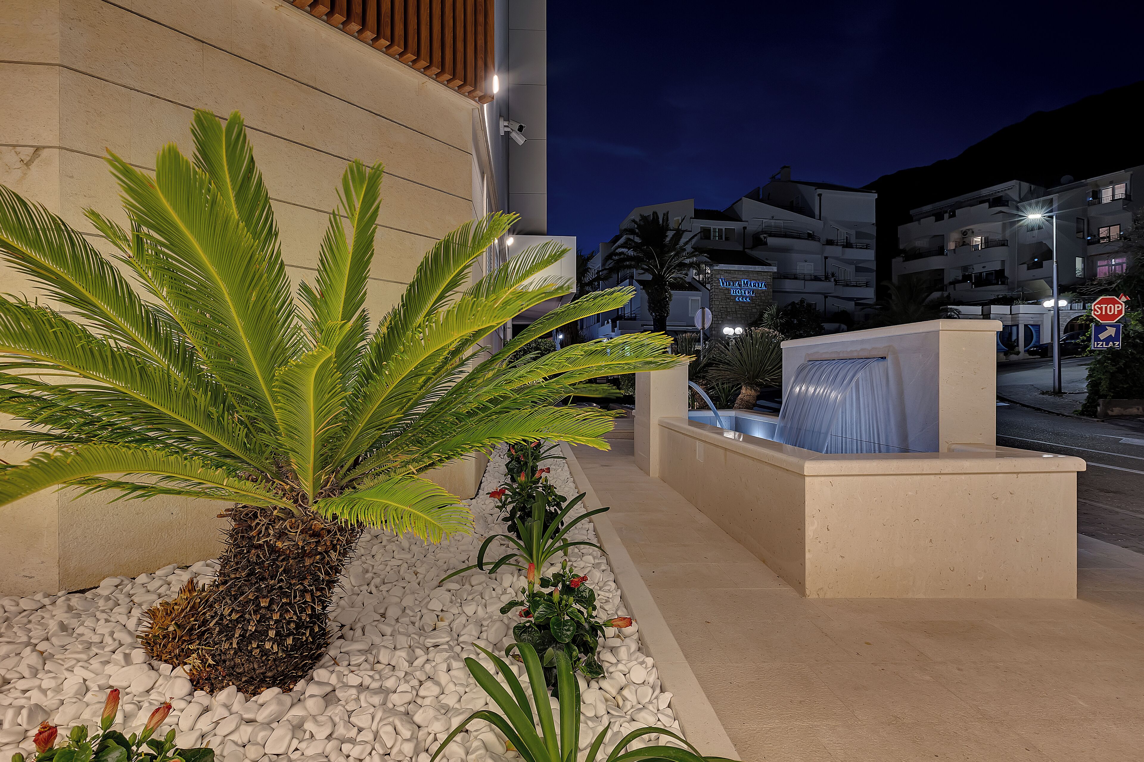 A modern building with a palm tree and a water feature in the foreground.