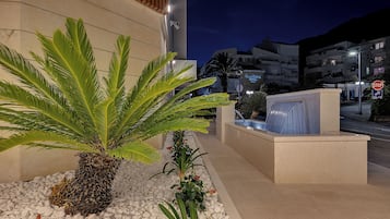 A modern building with a palm tree and a water feature in the foreground.