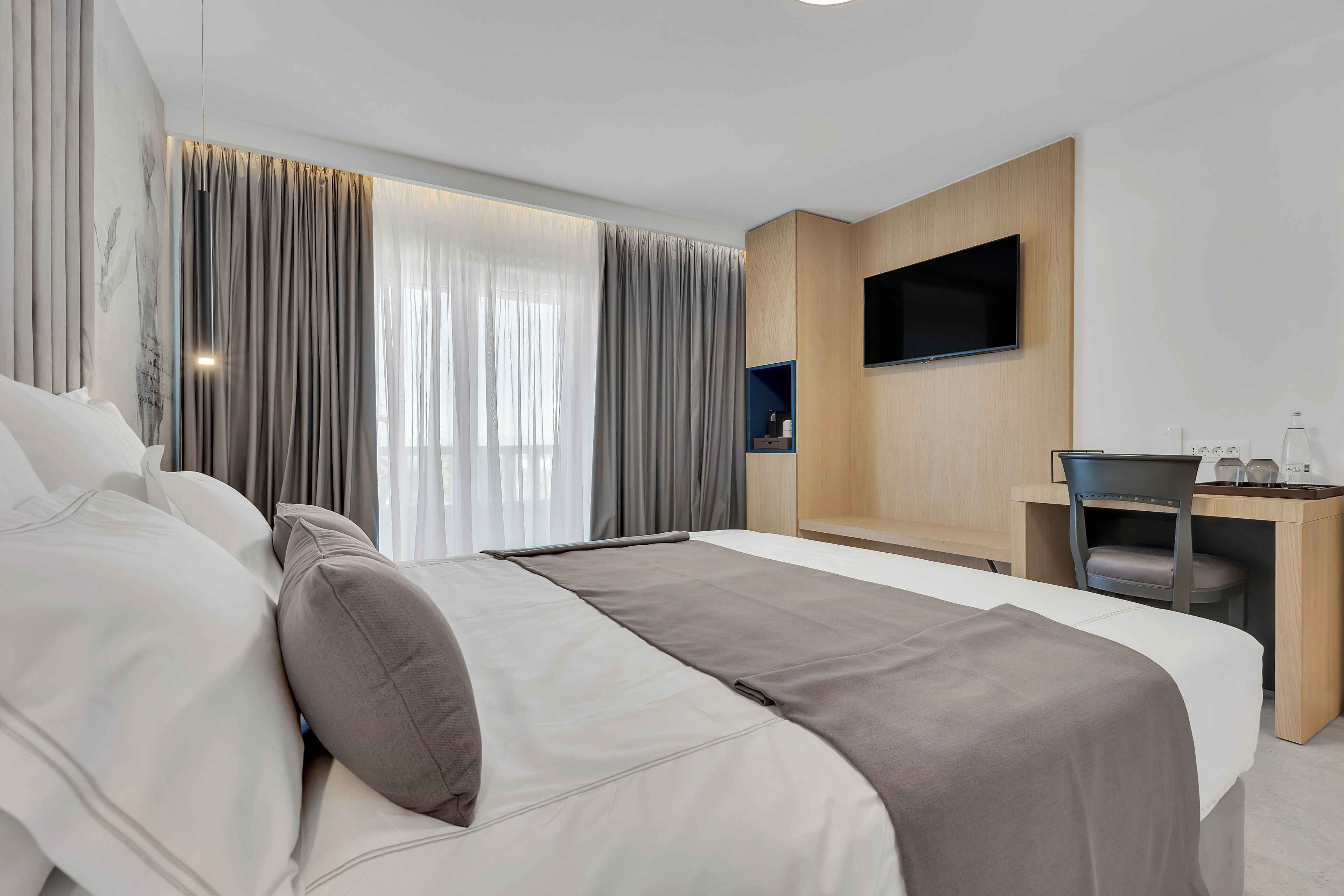 Een moderne hotelkamer met een groot bed, een bureau en een flatscreen televisie.