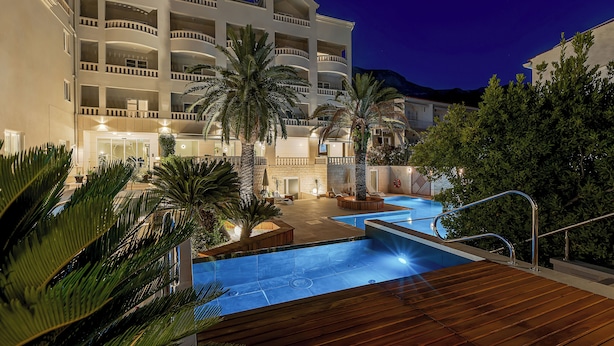 Un hotel con varios balcones, piscina y palmeras.
