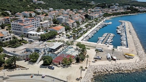 Vista aérea de un pueblo costero con un puerto deportivo, edificios residenciales y una zona de playa.