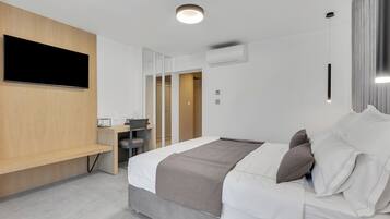 Una habitación de hotel moderna con una cama, un escritorio, un televisor de pantalla plana y un banco empotrado.