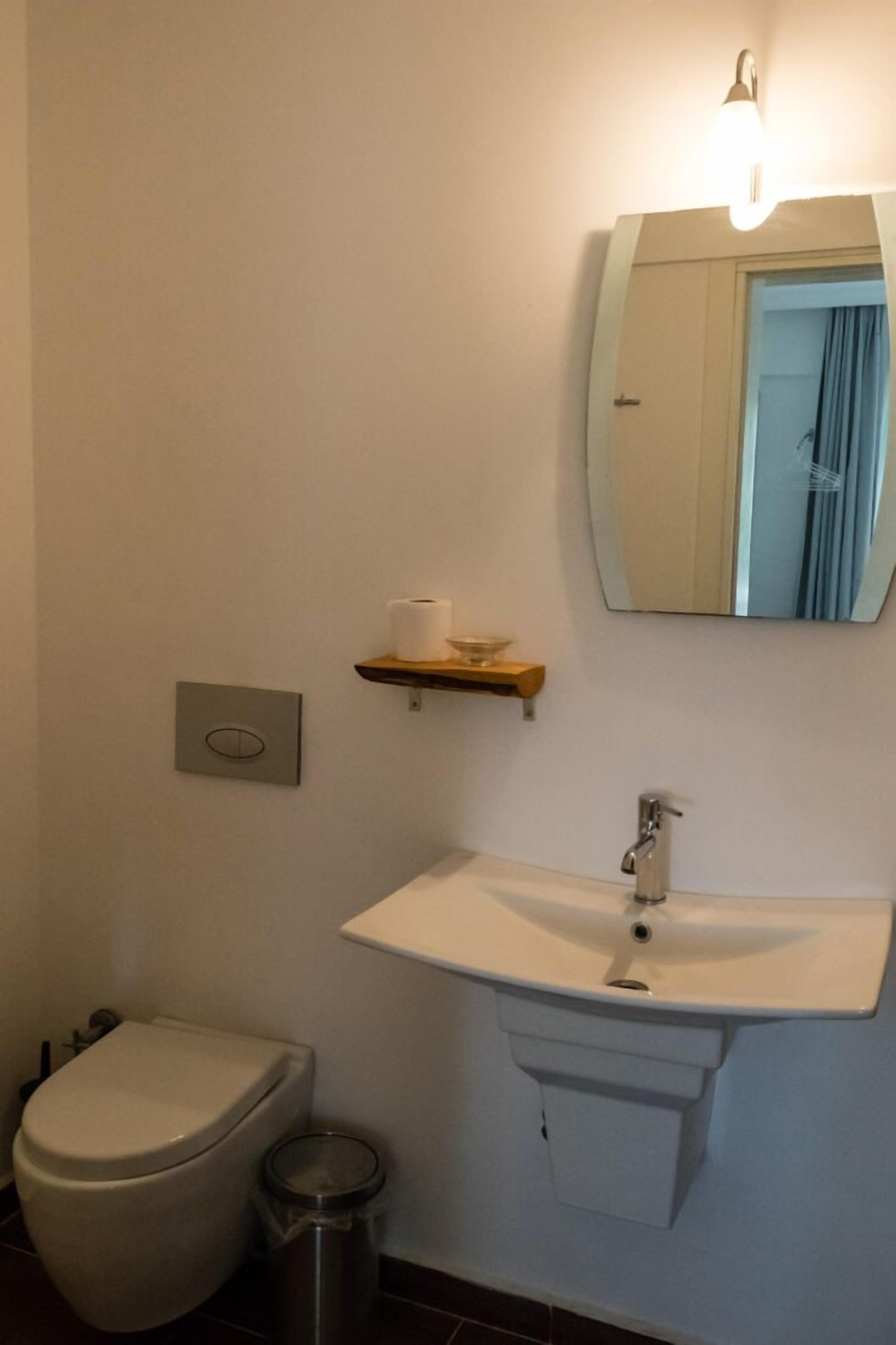 Ein Badezimmer mit Toilette, Waschbecken und Spiegel.