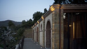 Un sendero que conduce a un edificio con arcos de piedra y una entrada de cristal.