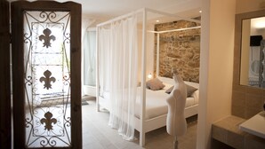 Un dormitorio con pared de piedra, cama con dosel y dosel blanco.