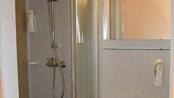 A bathroom with a glass shower enclosure, a sink, and a mirror.