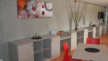 Une cuisine moderne avec des meubles gris, un grand tableau abstrait et des chaises rouges.
