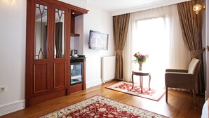 Una habitación con un armario de madera, un televisor, un radiador, una silla y un tapete rojo y blanco.