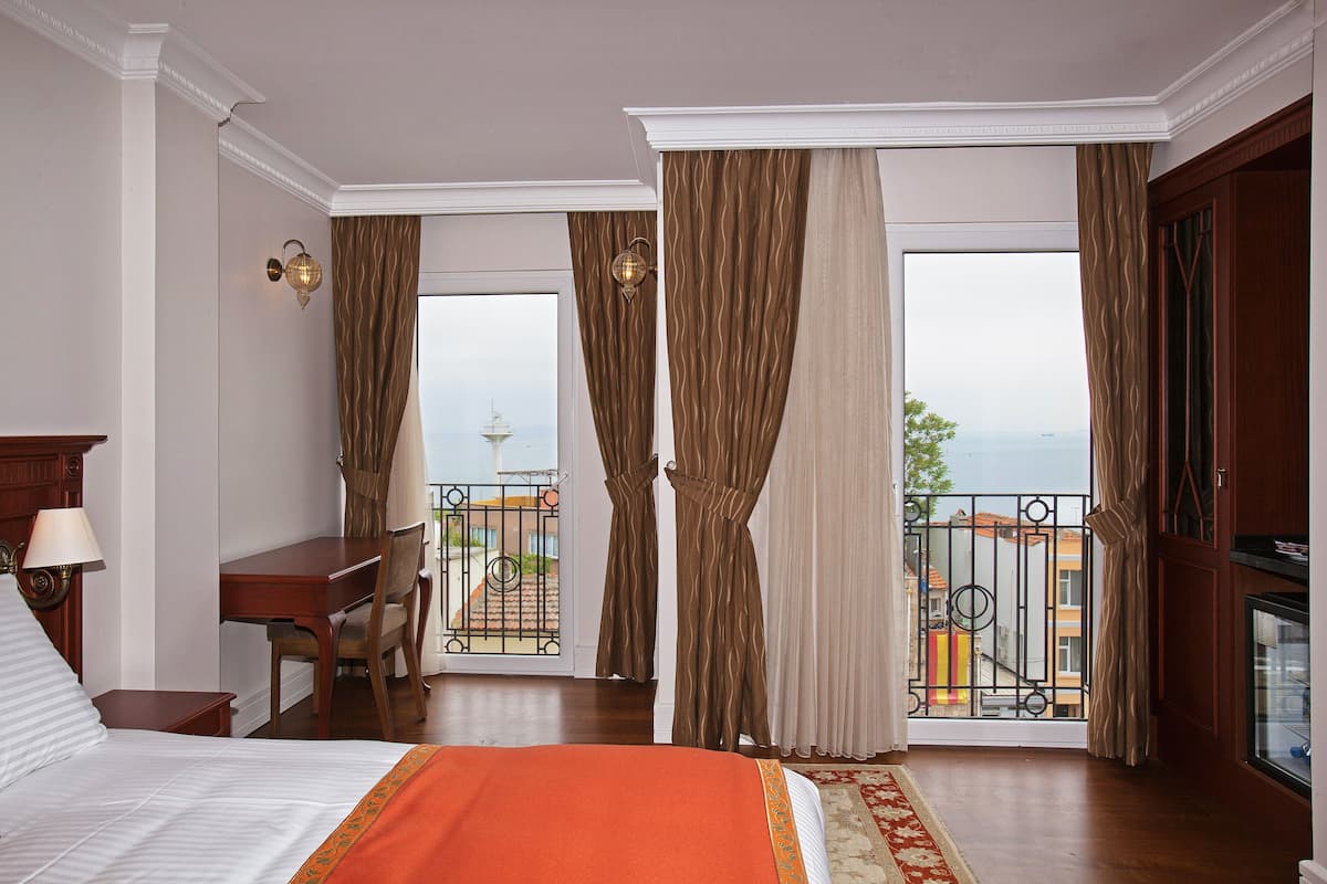 A hotel room with a bed, desk, and balcony with a view.
