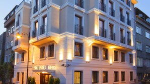 Un hotel de varios pisos con un diseño arquitectónico clásico, con balcones y una entrada bien iluminada.