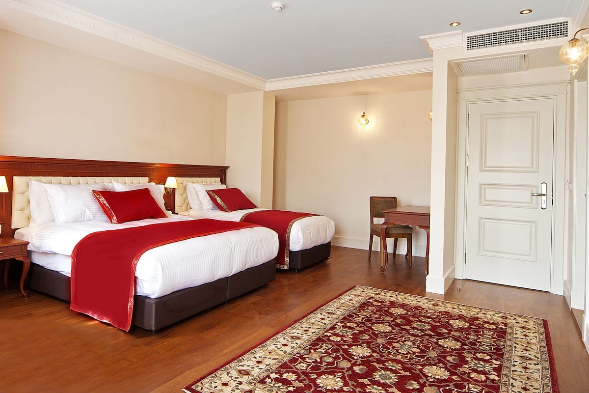 A hotel room with two beds, a desk, and a chair.