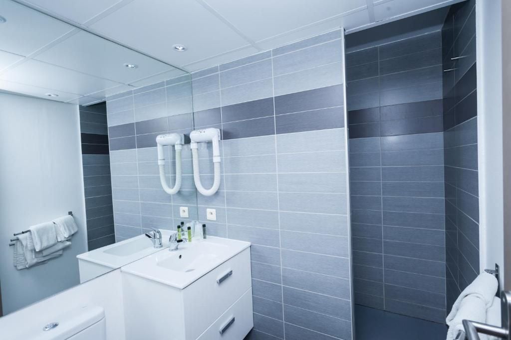 A modern bathroom with a white sink, mirror, and towel rack.