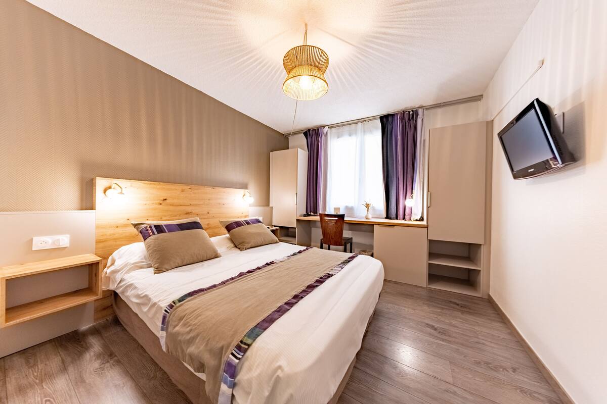 Una habitación de hotel moderna con una cama grande, un escritorio y un televisor.