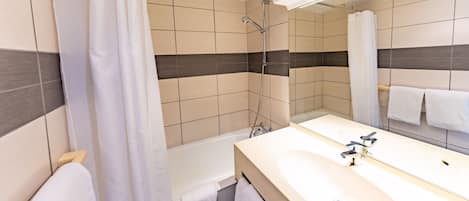A modern bathroom with a bathtub, shower, and sink.