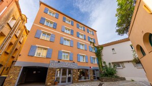 A multi-story hotel with a stone facade and blue shutters, featuring a storefront named "Princes de Catalogne."