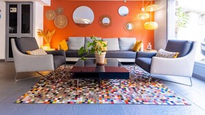 A modern living room with a sofa, two armchairs, a coffee table, and a colorful rug.