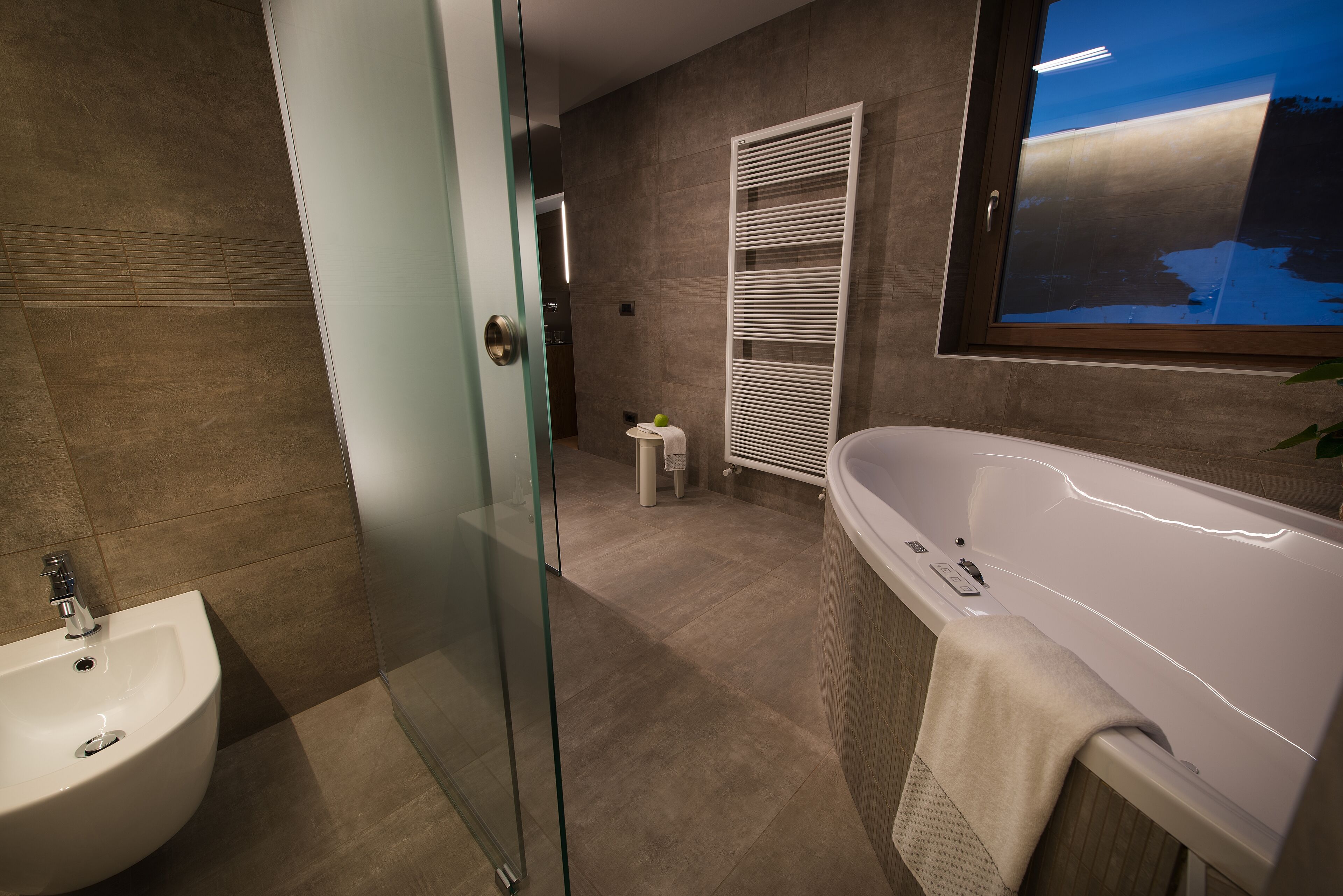 A modern bathroom with a glass shower enclosure, a freestanding bathtub, and a pedestal sink.