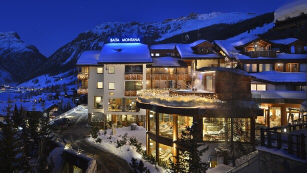 A multi-story hotel with a snow-covered roof, a balcony with a wooden railing, and a sign reading "BAITA MONTANA". - Hotel Baita Montana (Livigno)