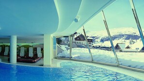 An indoor swimming pool with a view of a snowy mountain landscape through large windows. - Hotel Baita Montana (Livigno)