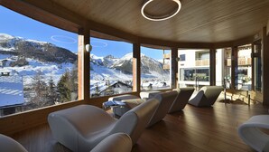 A modern interior with large windows offering a view of a snowy mountain landscape. - Hotel Baita Montana (Livigno)