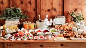 A wooden table with various food items, drinks, and a piano. - Landhaus Koller (Gosau)