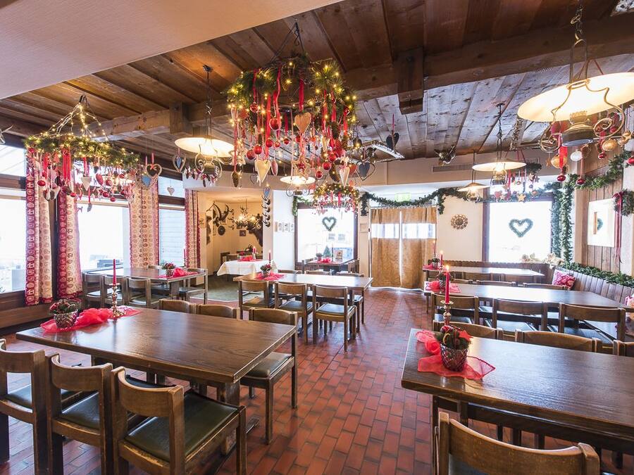 En restaurant med træborde og stole, festlig pynt og en gulv af mursten.