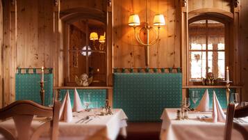 Un restaurant aux murs lambrés, aux banquettes recouvertes d’un tissu turquoise et agrémenté d’un lustre.