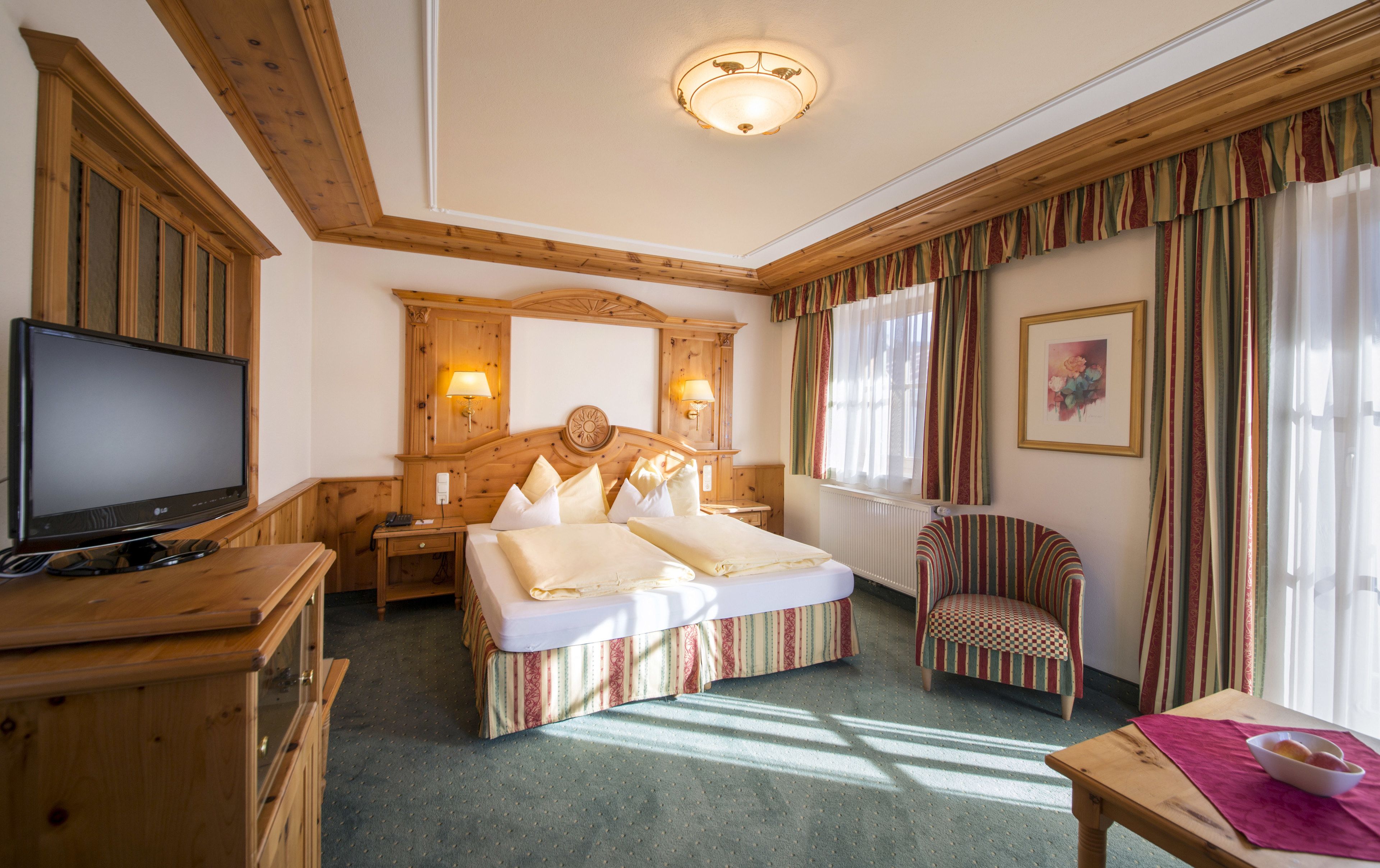 A hotel room with a wooden bed, a television, a desk, and a chair.