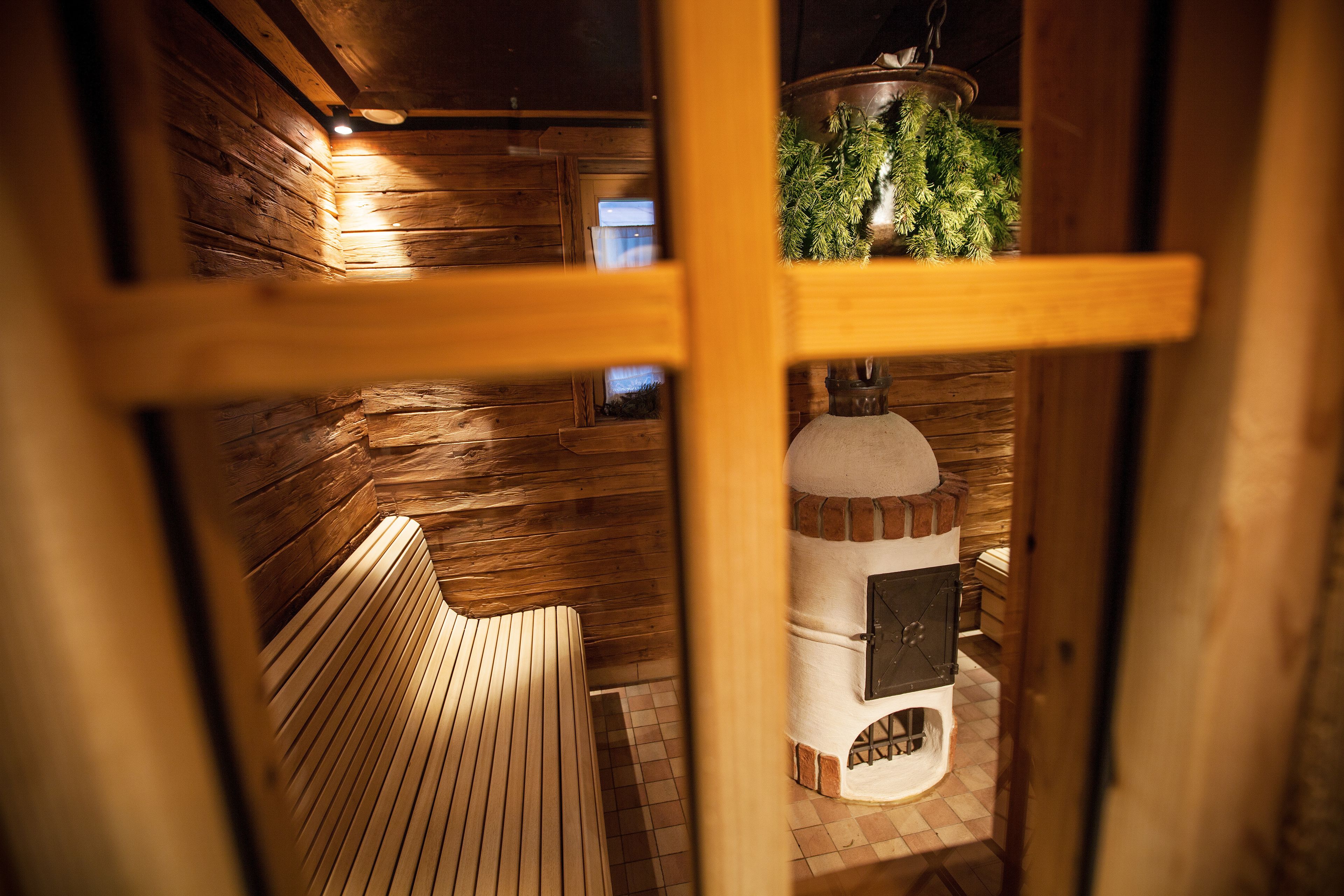 A wooden interior with a bench, a fireplace, and a hanging plant.
