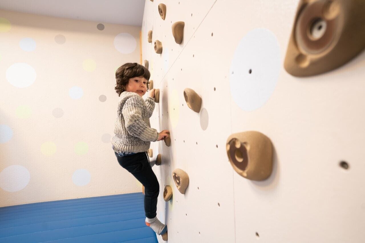 A child climbing a wall with handholds.