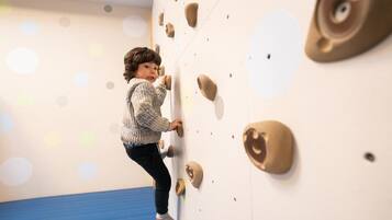A child climbing a wall with handholds.