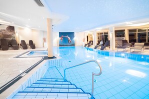 A swimming pool with a mural of a person jumping into the water, surrounded by lounge chairs and a staircase leading down to the pool.