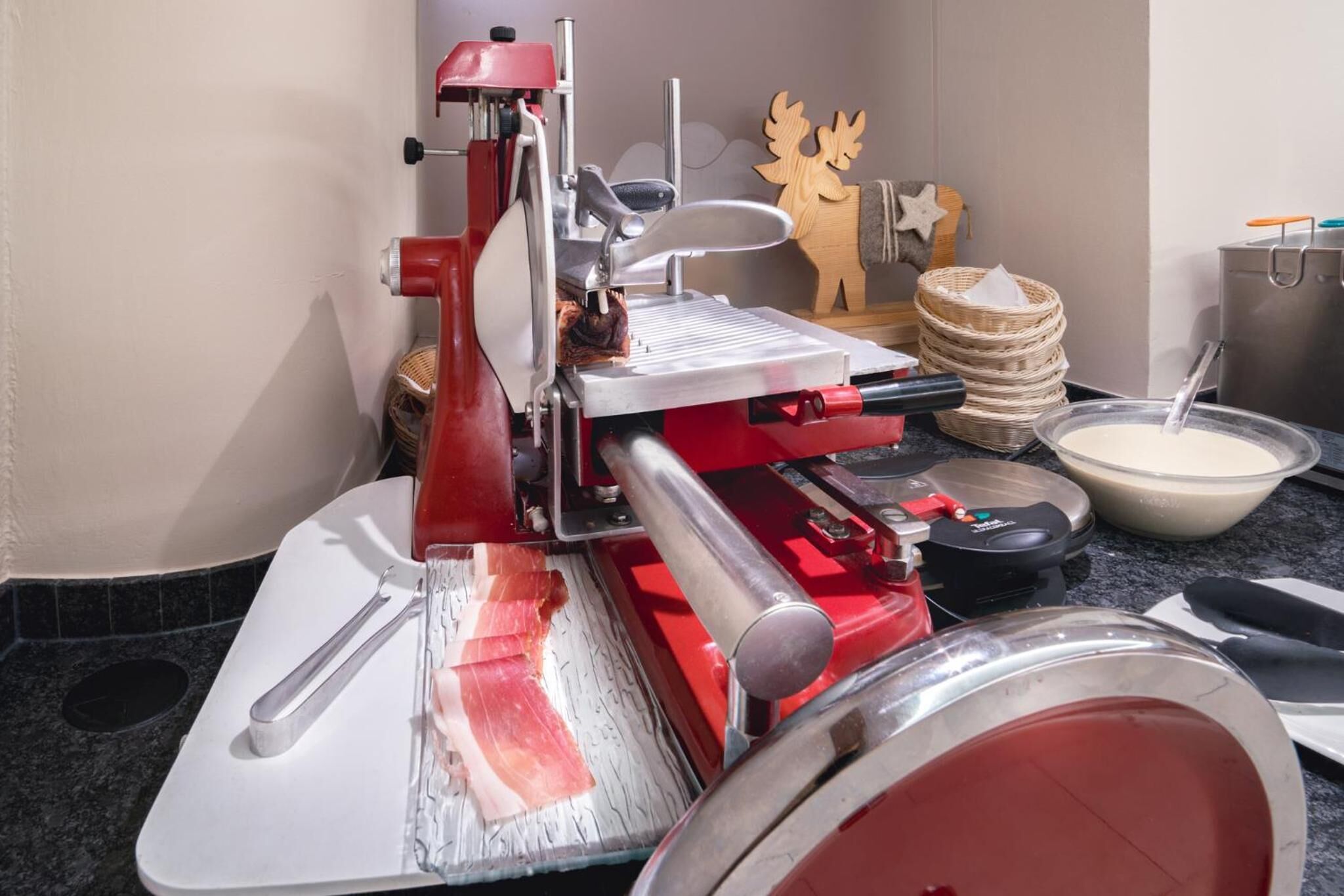 Una cucina con un affettatrice per carne rossa, una ciotola di latte e una decorazione di renna in legno.