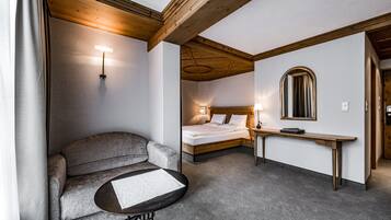 Una camera d'albergo con un divano, un tavolino, un letto, un comodino e uno specchio.