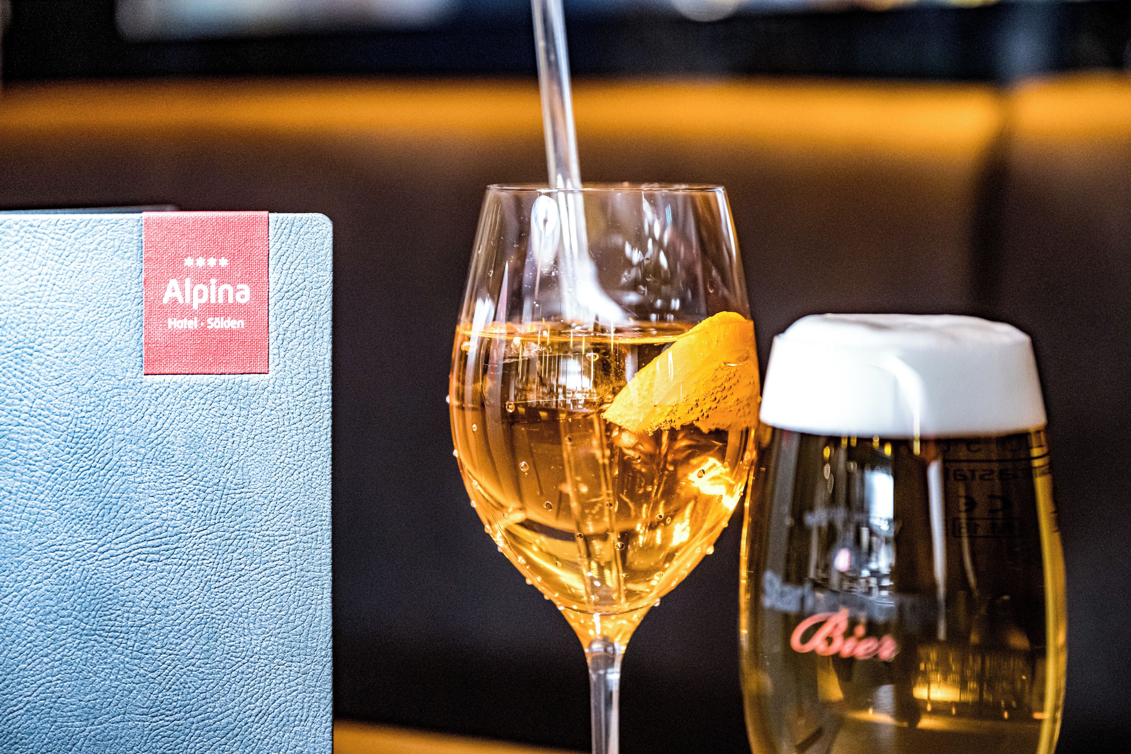A glass of beer with a lemon slice and a bottle labeled "Bier" next to a menu or booklet with a red label.