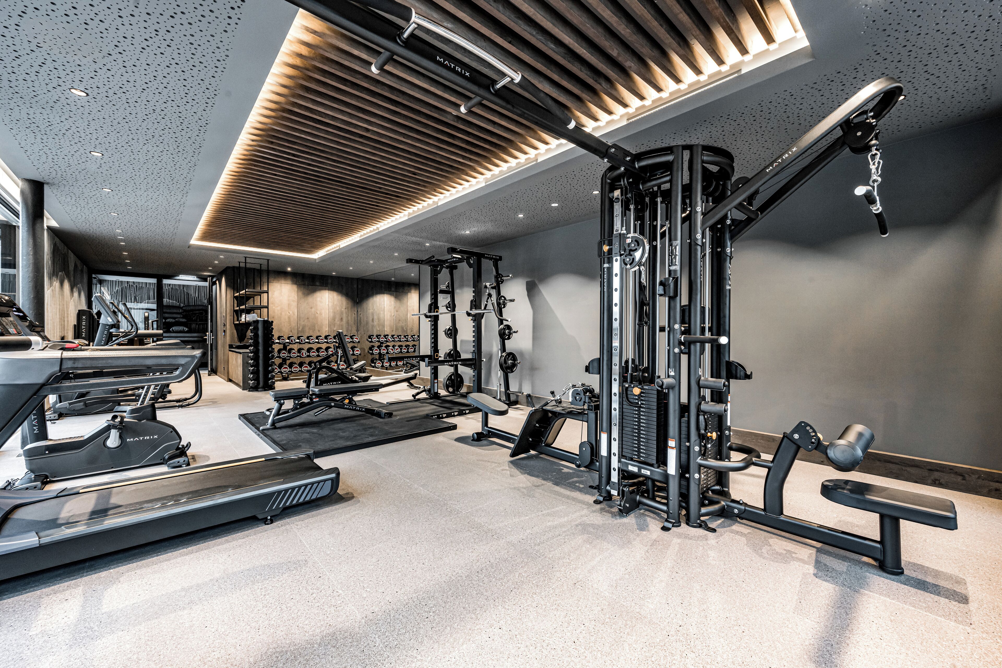 Un gimnasio moderno con diversos equipos de ejercicio, cinta de correr y banco.