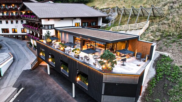 A modern hotel with a rooftop patio area featuring outdoor seating and a view of the surrounding landscape.