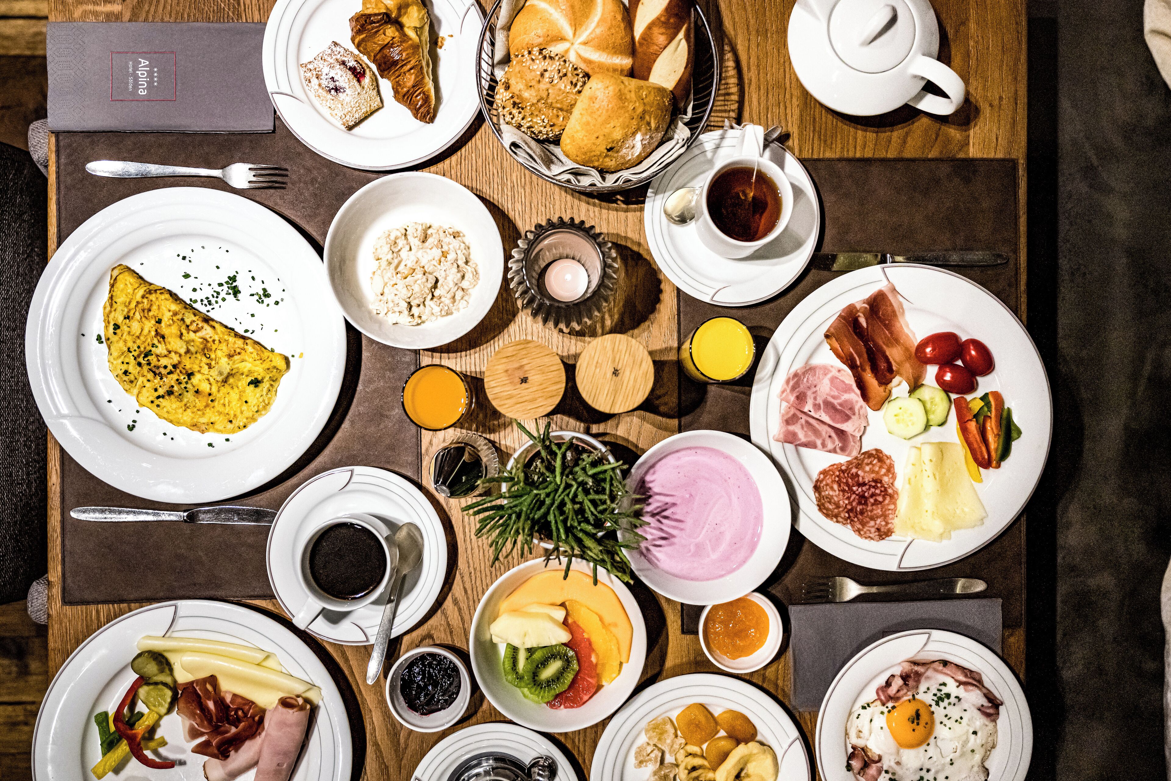 Ein reichhaltiges Frühstücksbuffet mit verschiedenen Speisen, darunter Eier, Fleisch, Früchte und Gebäck.
