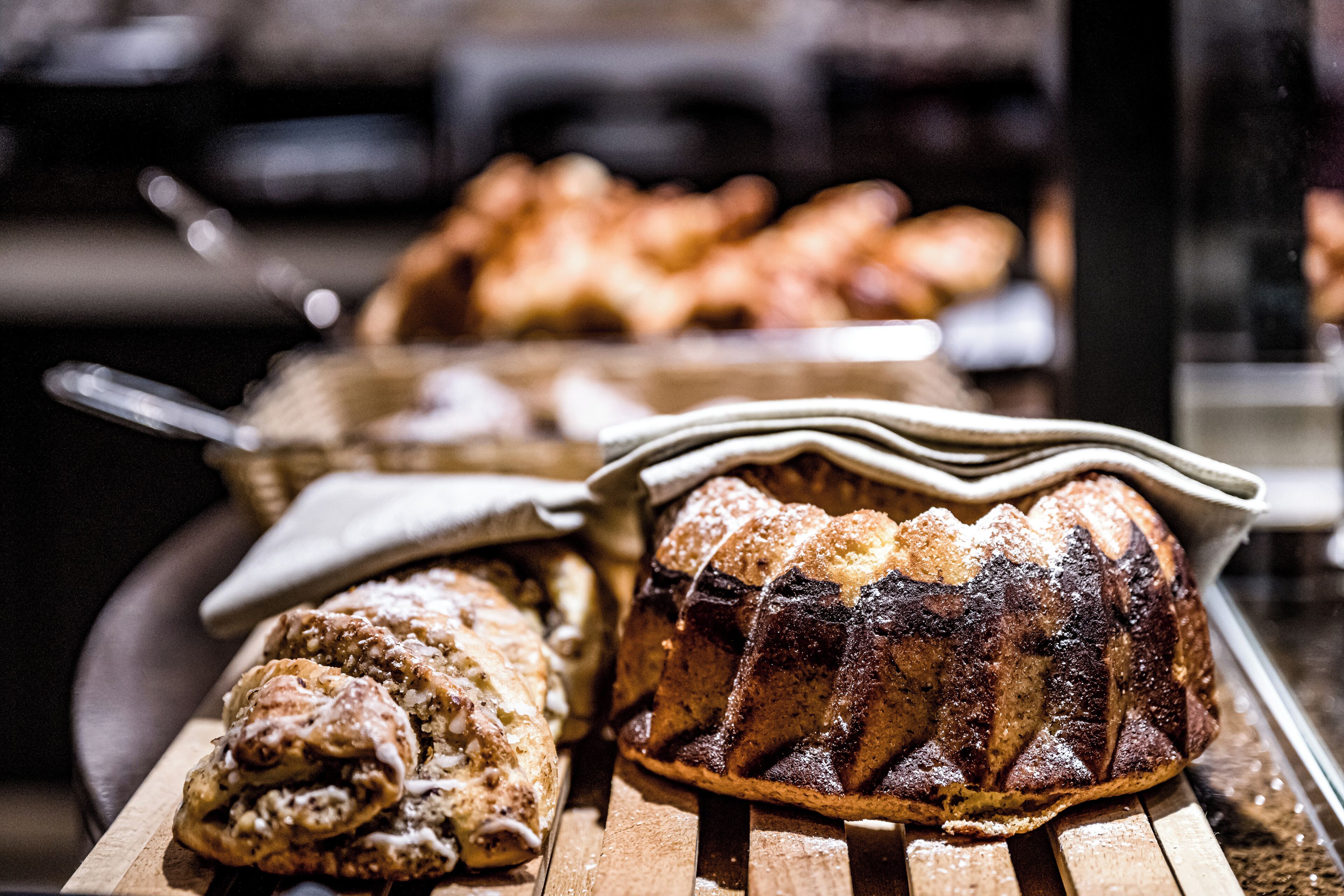 Verschiedene Backwaren auf Holztabletts, darunter ein Brot und Gebäck.